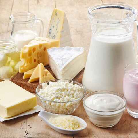 A spread of dairy products - cheeses, milk, and yogurt - displayed on a table.