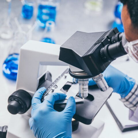 A male health care researcher uses a microscope in a life sciences laboratory.